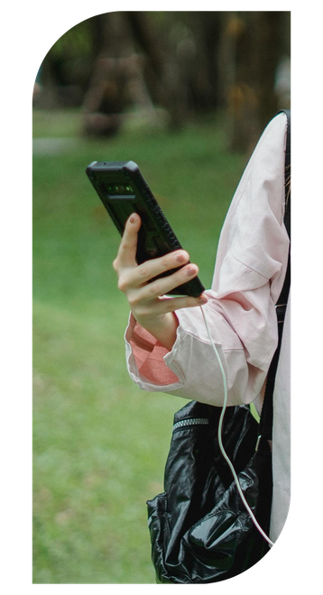 A person is holding a cell phone in their hand while carrying a backpack.