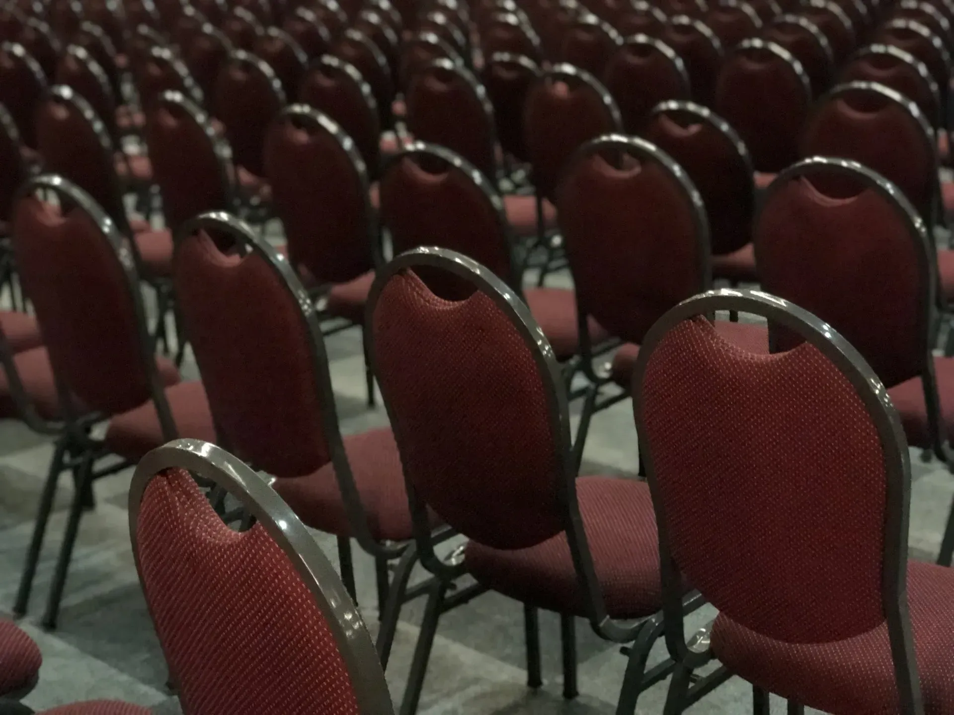 Fileiras de cadeiras vermelhas vazias em um auditório.