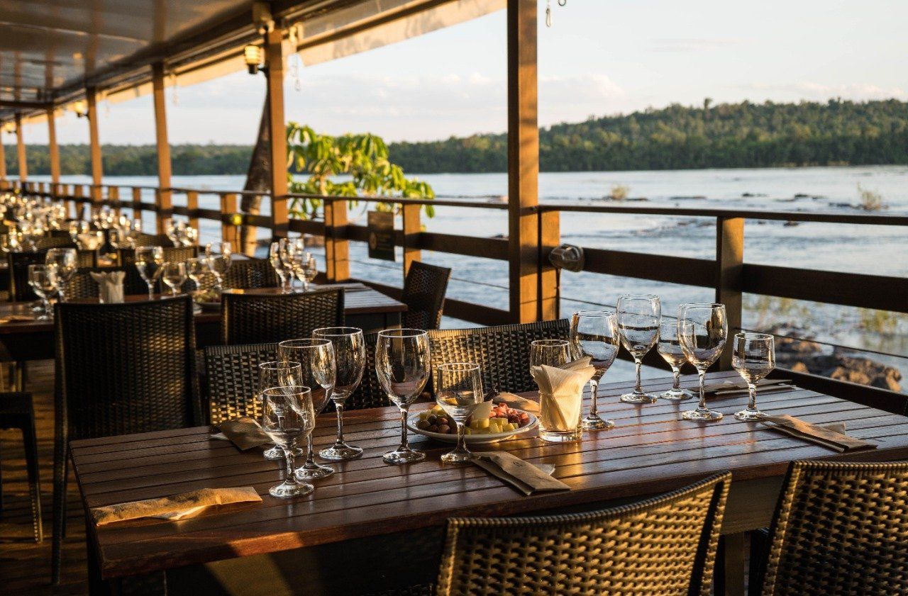 Mesas de restaurante ao ar livre preparadas para os clientes, com vista para um rio.