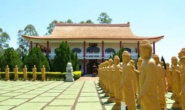 Um templo budista com estátuas douradas em fileiras, em um dia ensolarado.