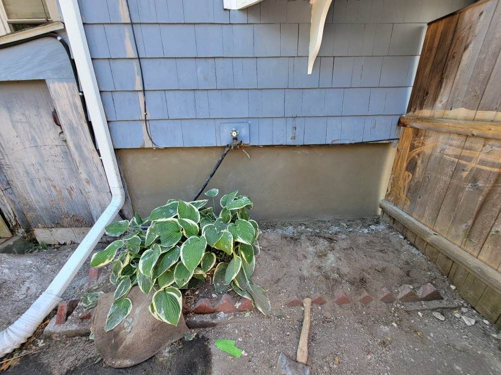 A potted plant is sitting in the dirt in front of a house.