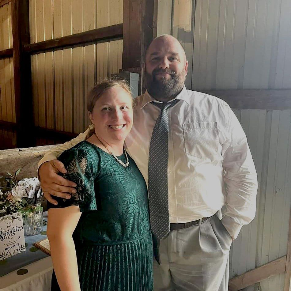 A man and a woman are posing for a picture in a barn.