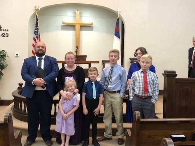 A group of people standing in front of a cross in a church.