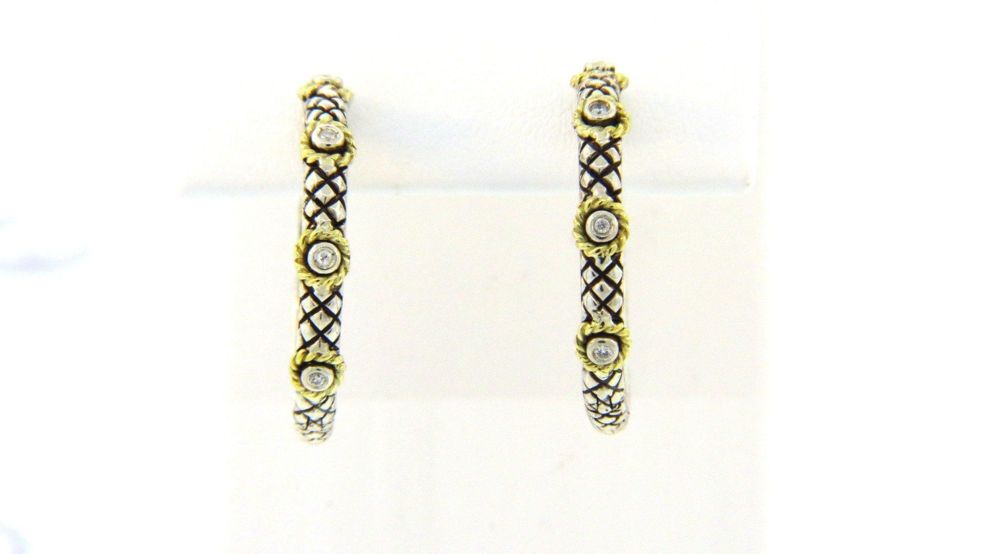 A pair of gold hoop earrings with diamonds on a white surface.
