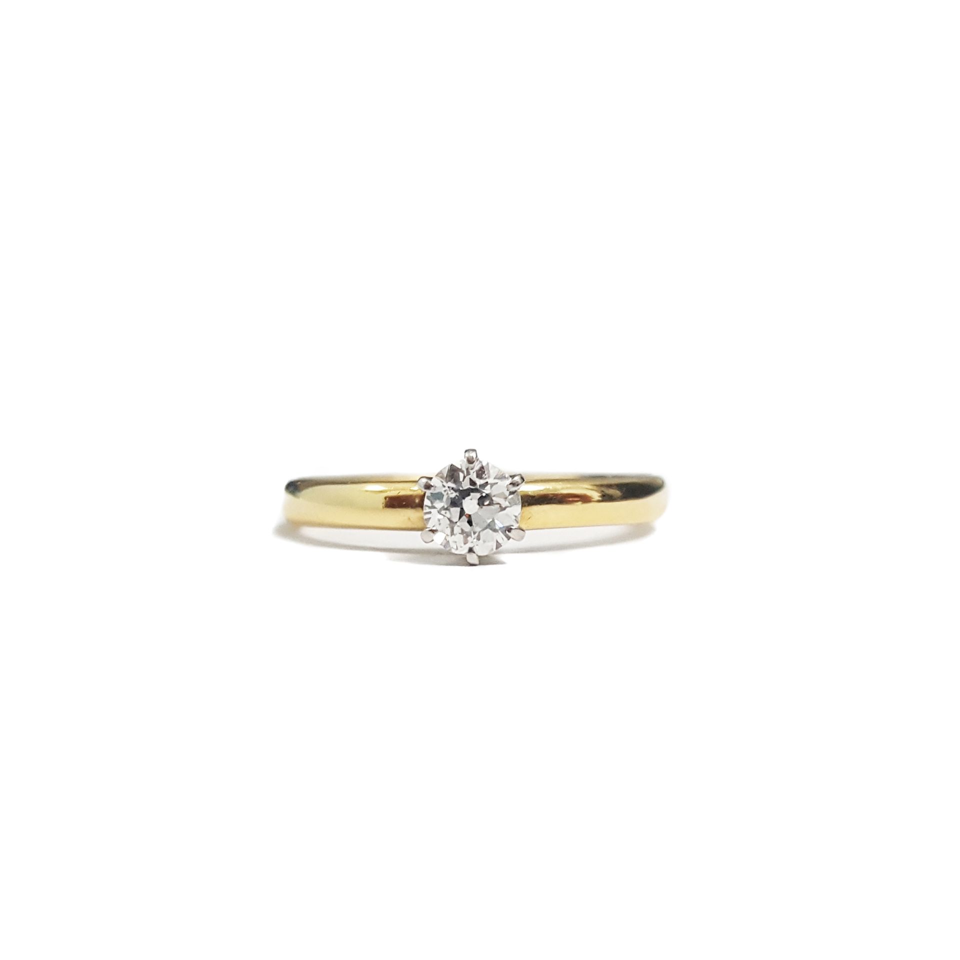 A yellow gold ring with a diamond in the center on a white background.