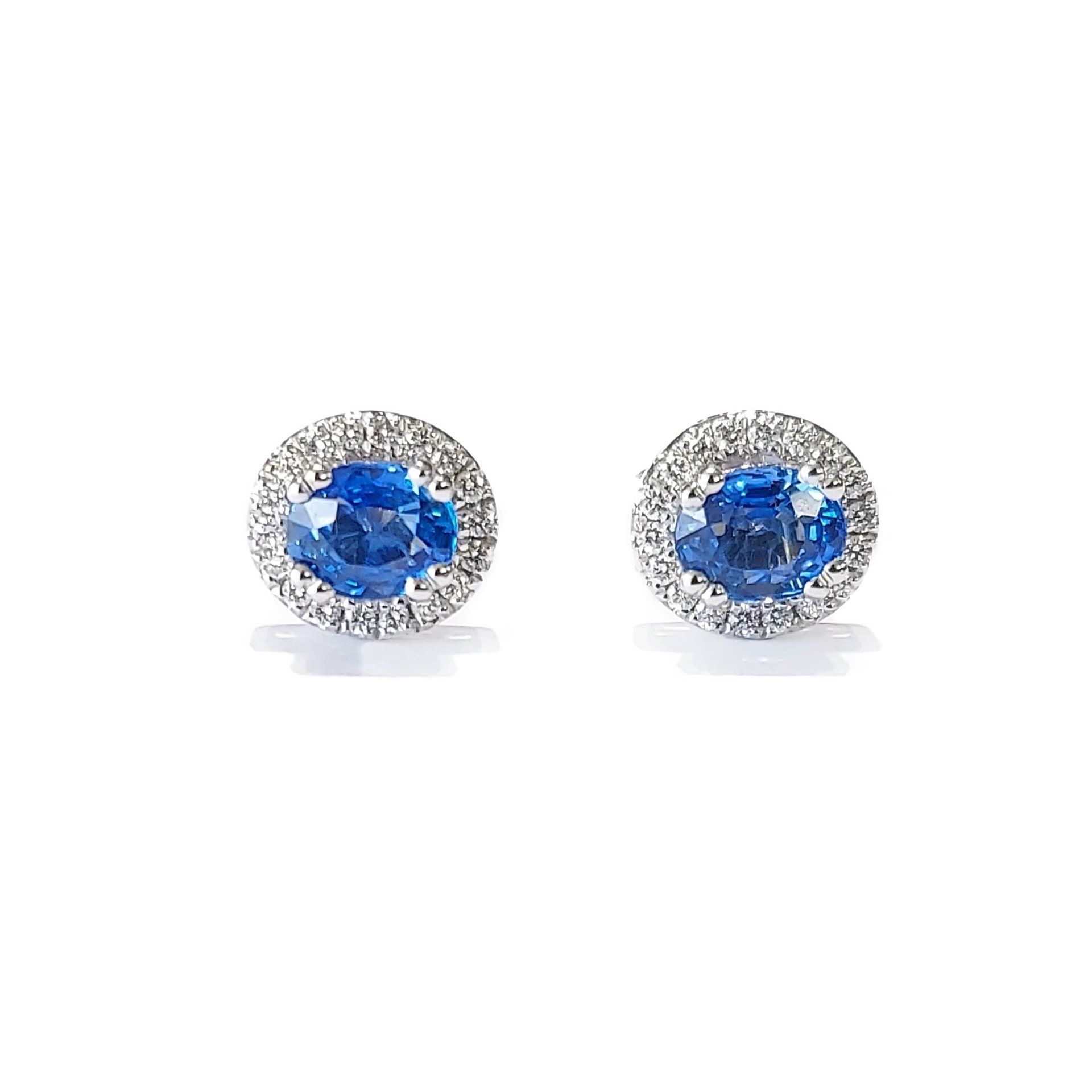 A pair of sapphire and diamond stud earrings on a white background.