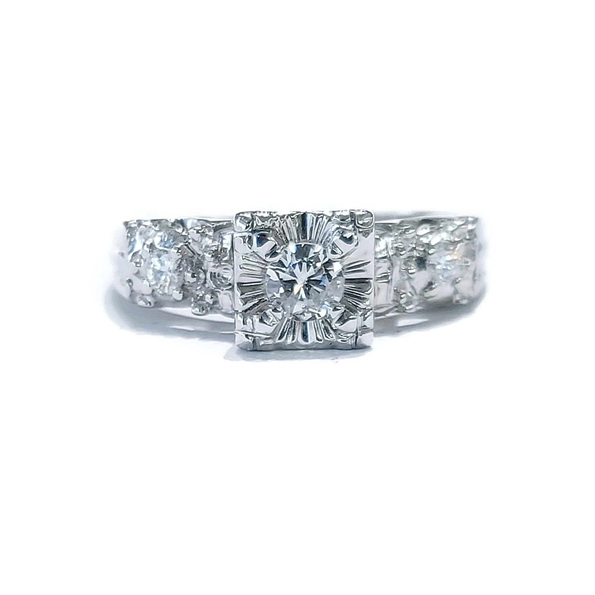 A white gold ring with a square diamond in the center surrounded by smaller diamonds.