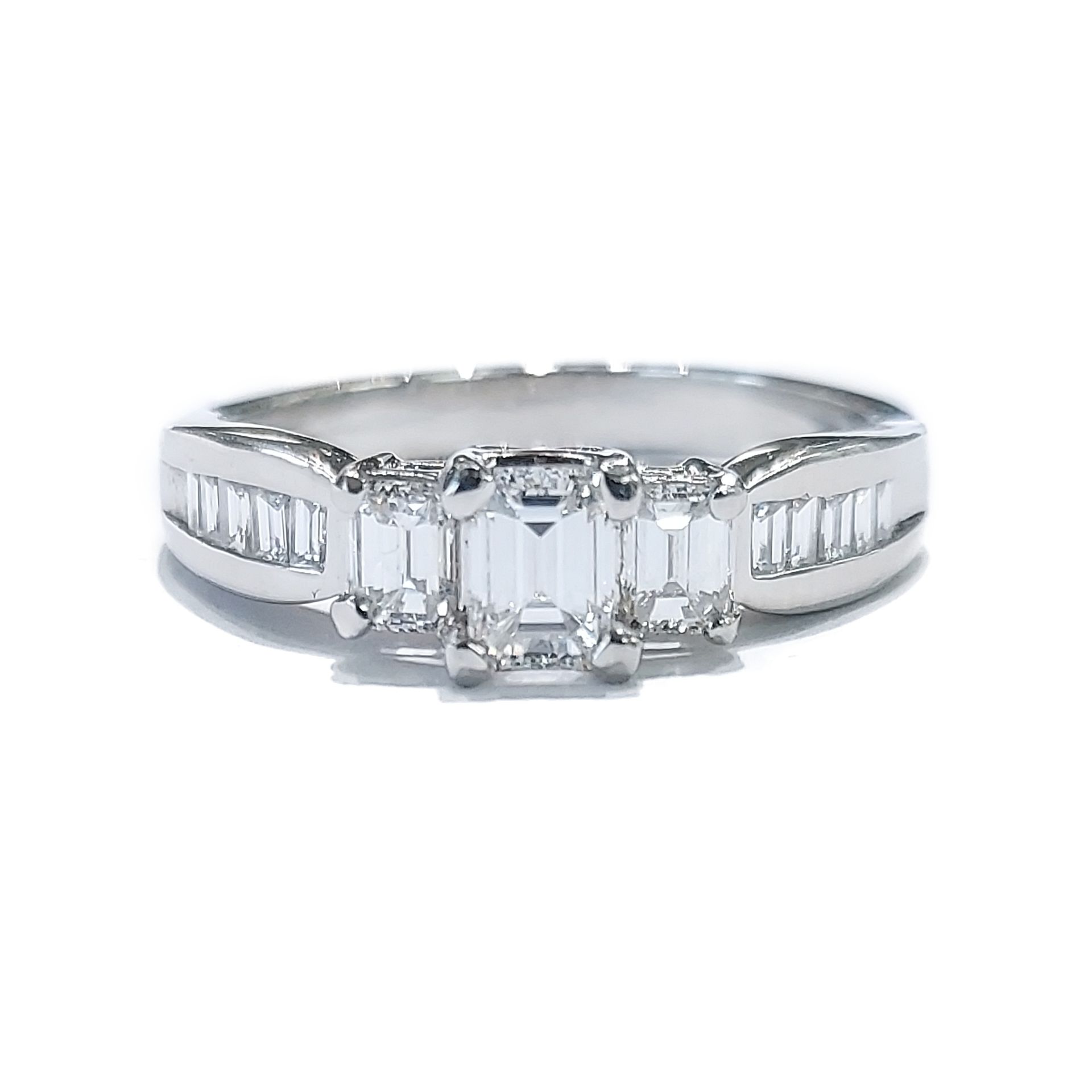 A white gold ring with emerald cut diamonds on a white background.