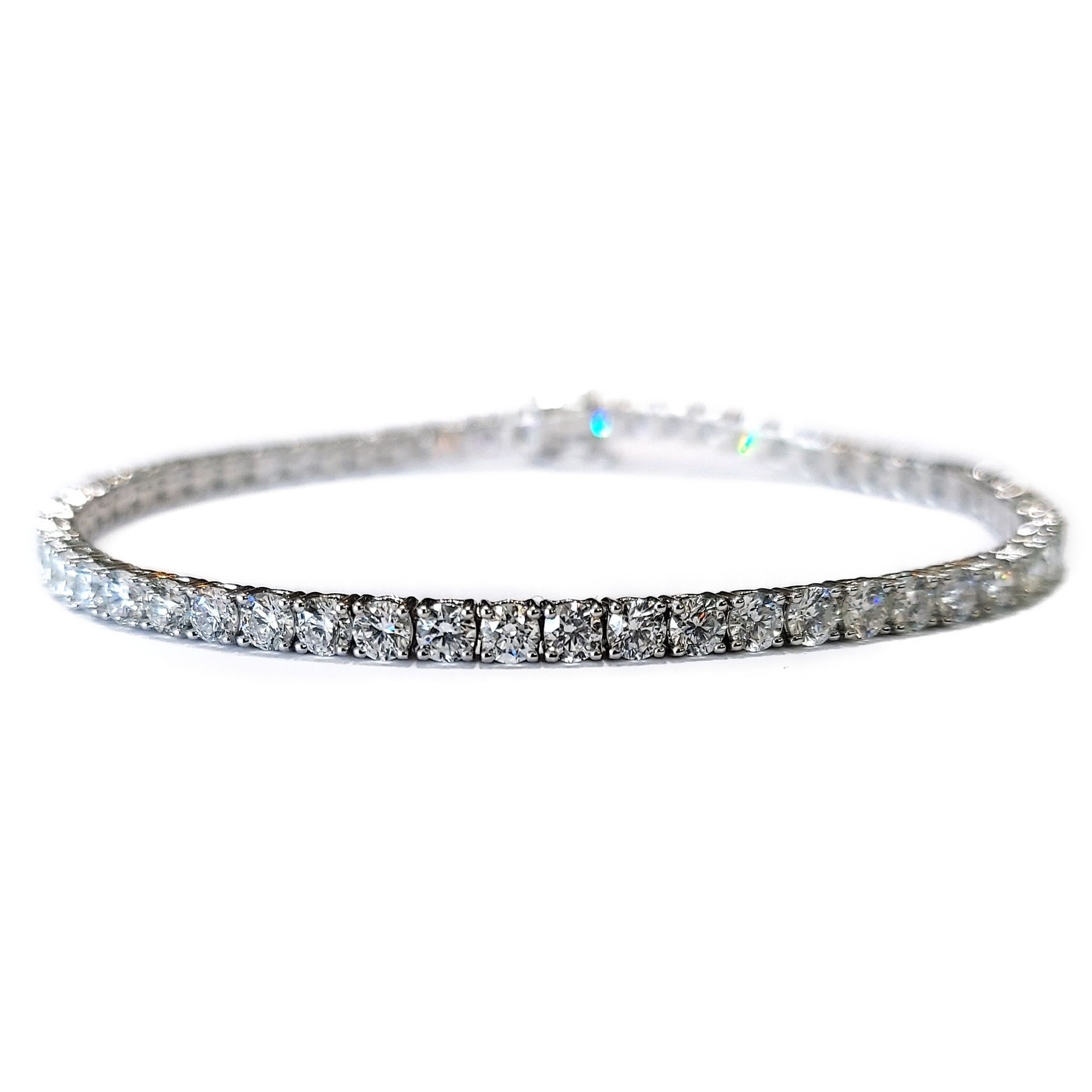 A close up of a diamond tennis bracelet on a white background.