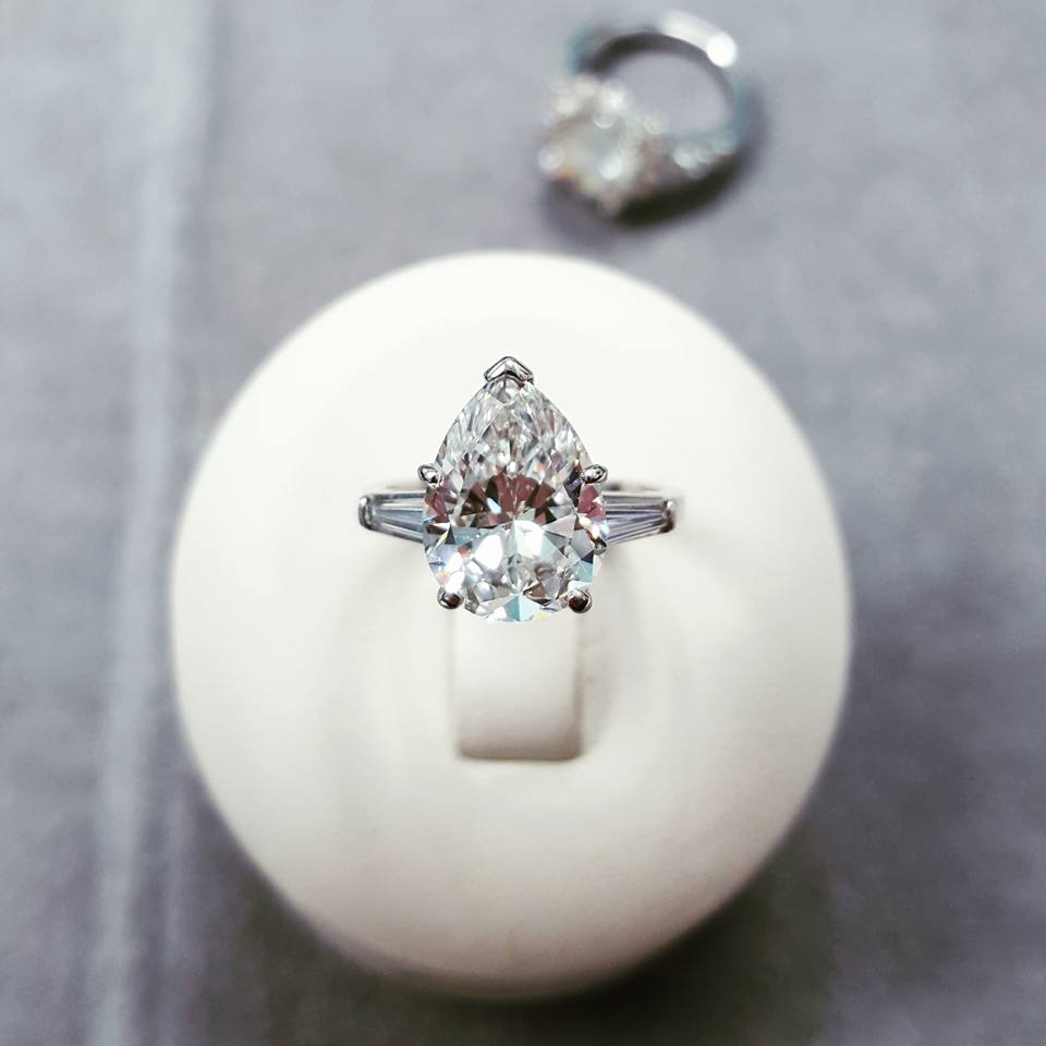 A pear shaped diamond ring is sitting on a white ball