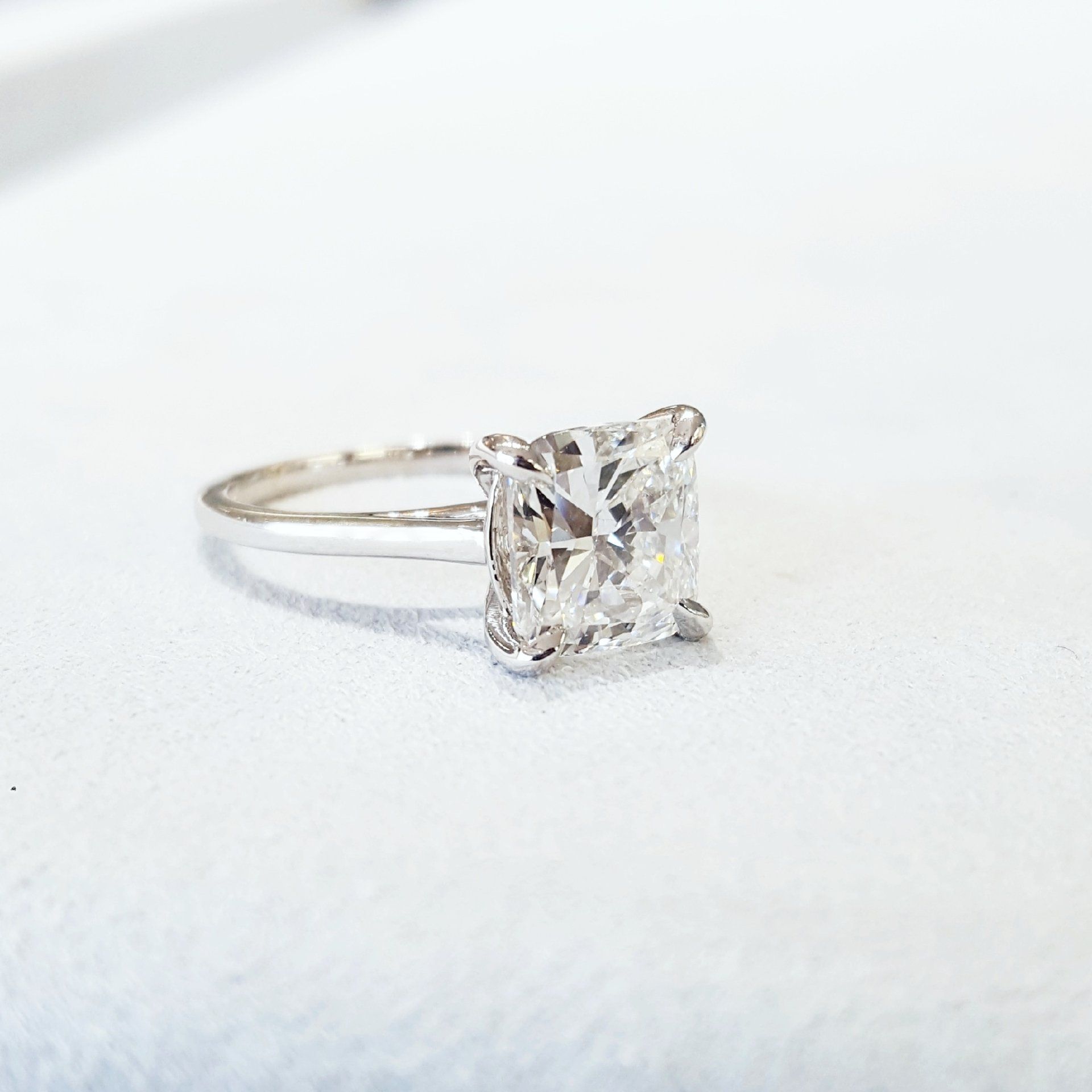 A close up of a diamond ring on a white surface.