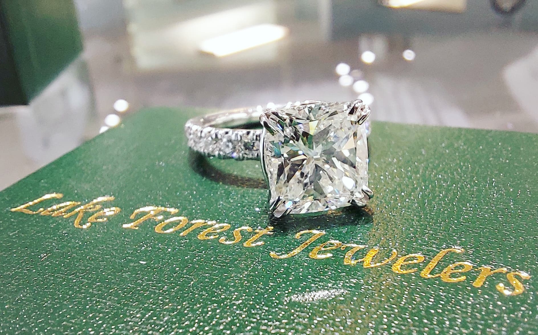 A diamond ring is sitting on top of a green box that says lake forest jewelers