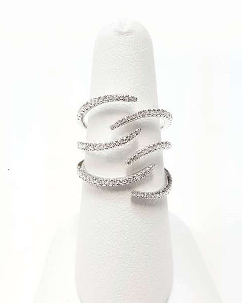 A silver ring with diamonds on it is sitting on a white ring holder.