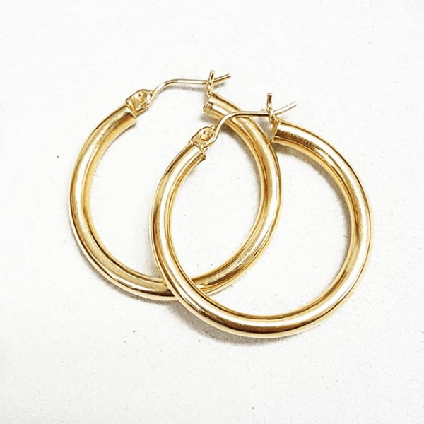 A pair of gold hoop earrings on a white surface