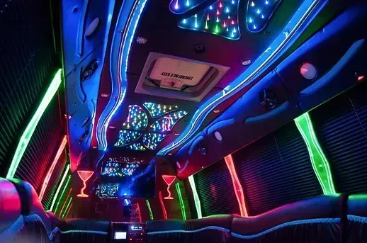 Inside a limousine with neon lights: blue, green, and red illuminate the walls and ceiling.
