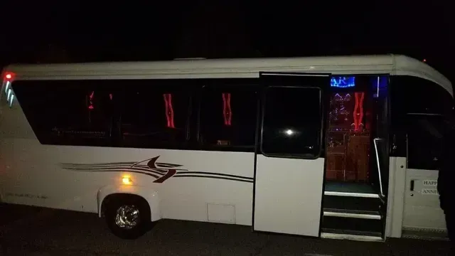 White bus at night with open door and illuminated interior.