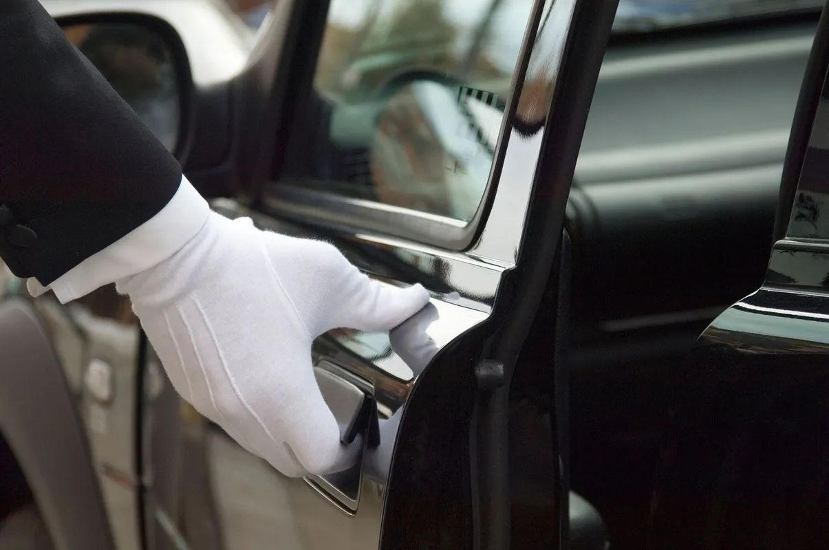 A gloved hand opens a car door.