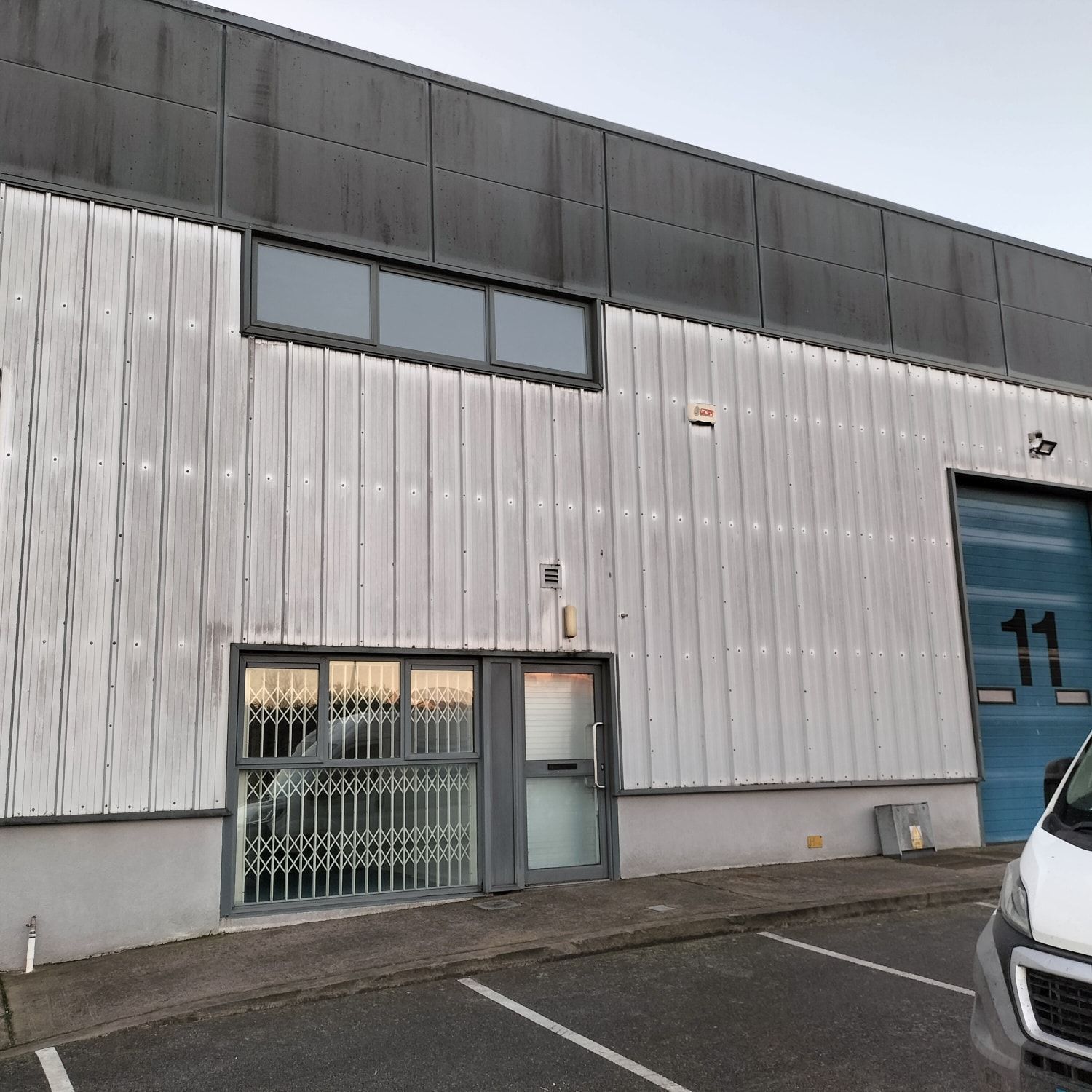 A white van is parked in front of a building with the number 11 on the door