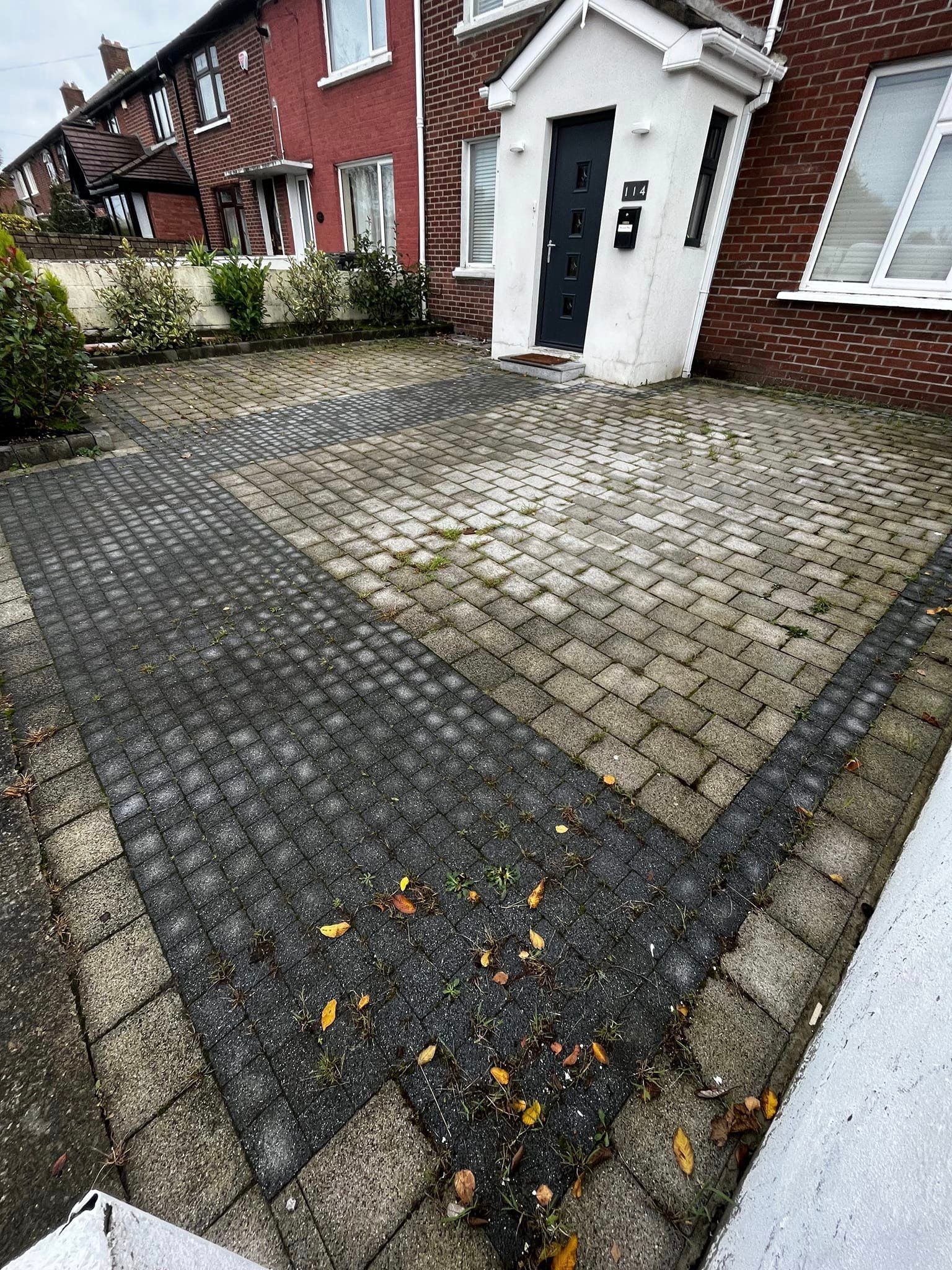 A brick driveway in front of a brick house.