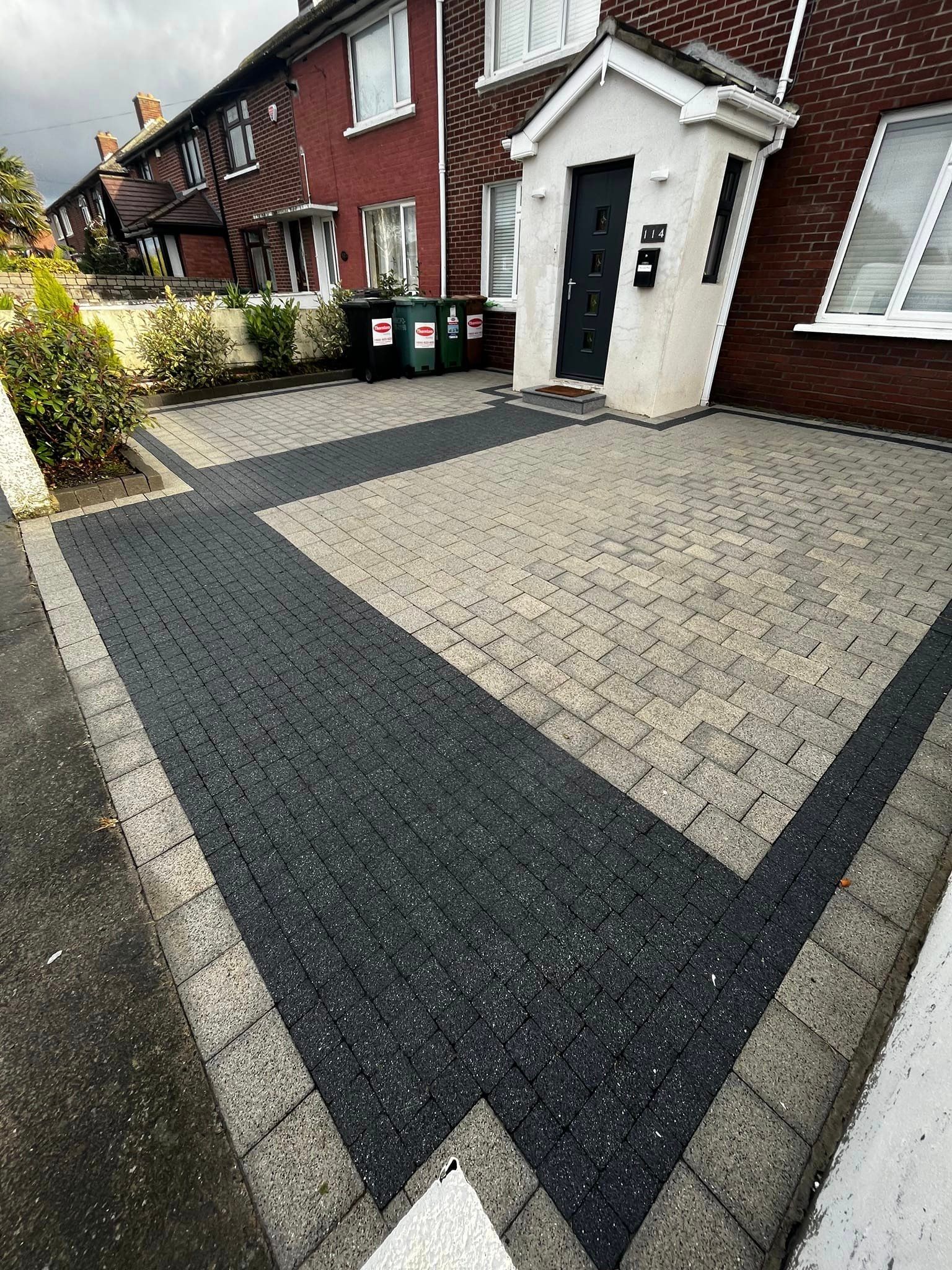 A black and white driveway in front of a brick house.