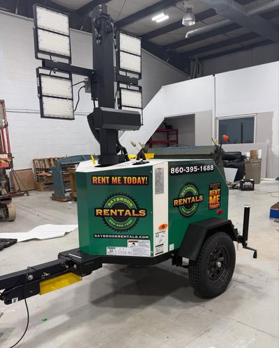 Green and white portable light tower on a trailer, labeled