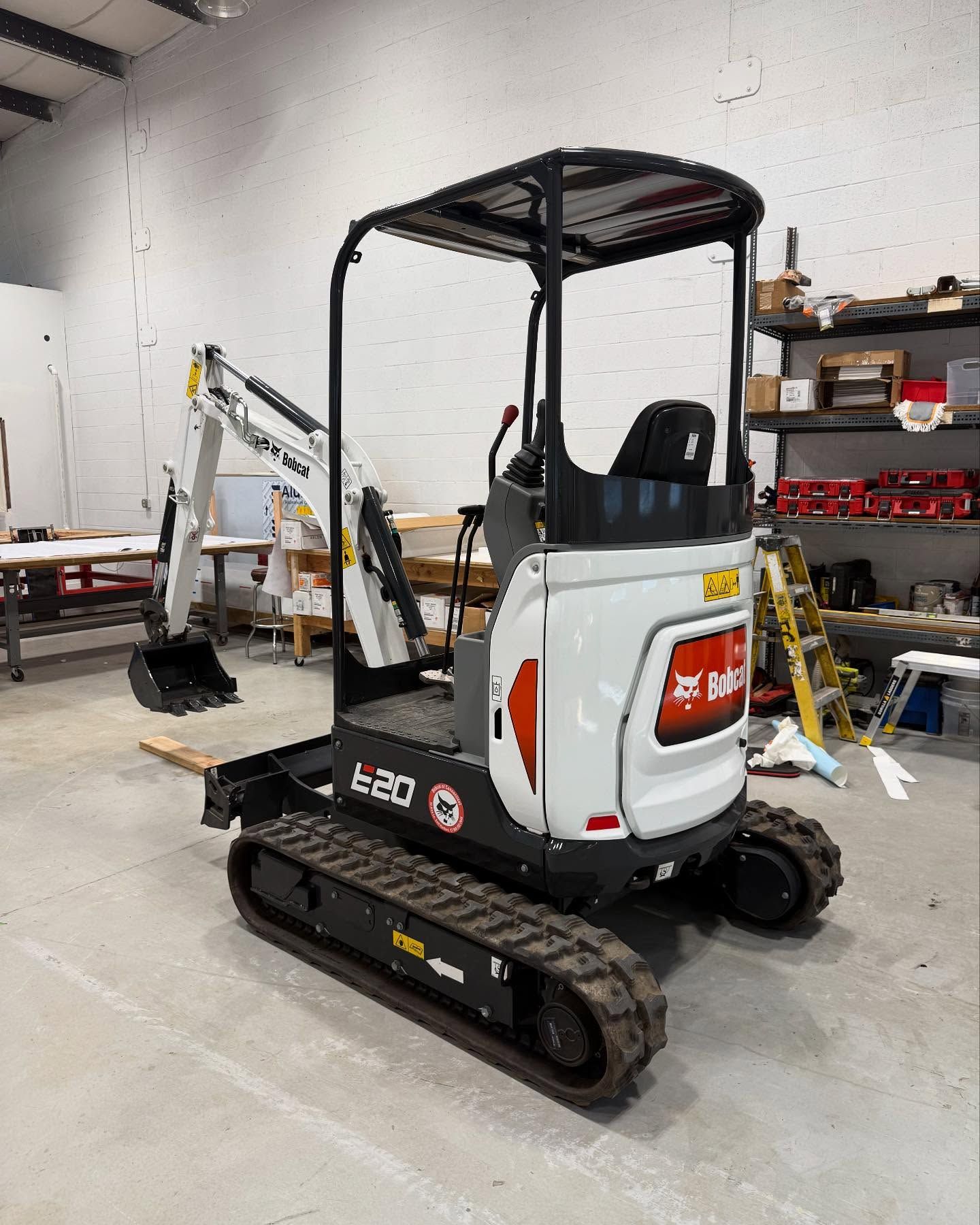 Bobcat E20 mini excavator, white and black, in a workshop.