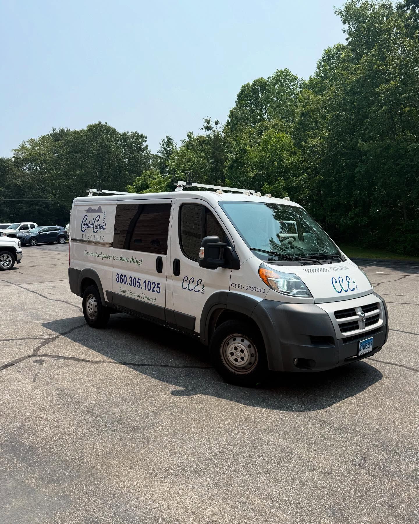 White Dodge van with logo and phone number parked in a lot on a sunny day.