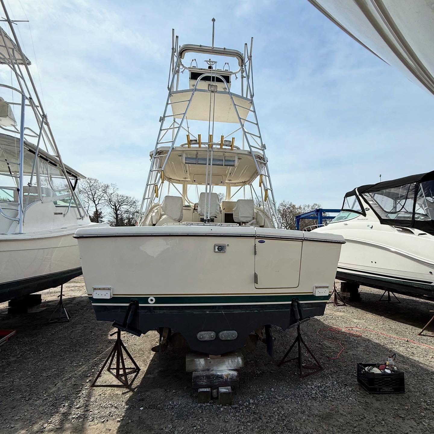 A white sport fishing boat on land, supported by stands. It has a tower and dark blue accents.