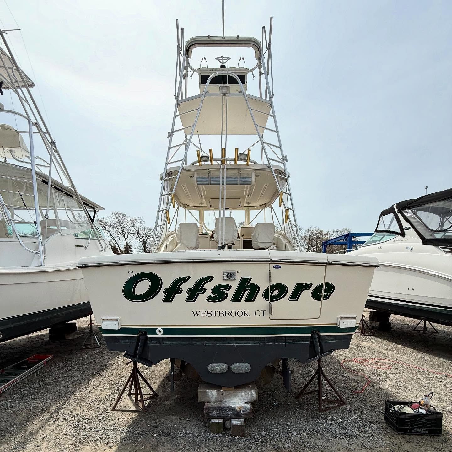 Offshore fishing boat on land, cream-colored with green lettering, blue hull.