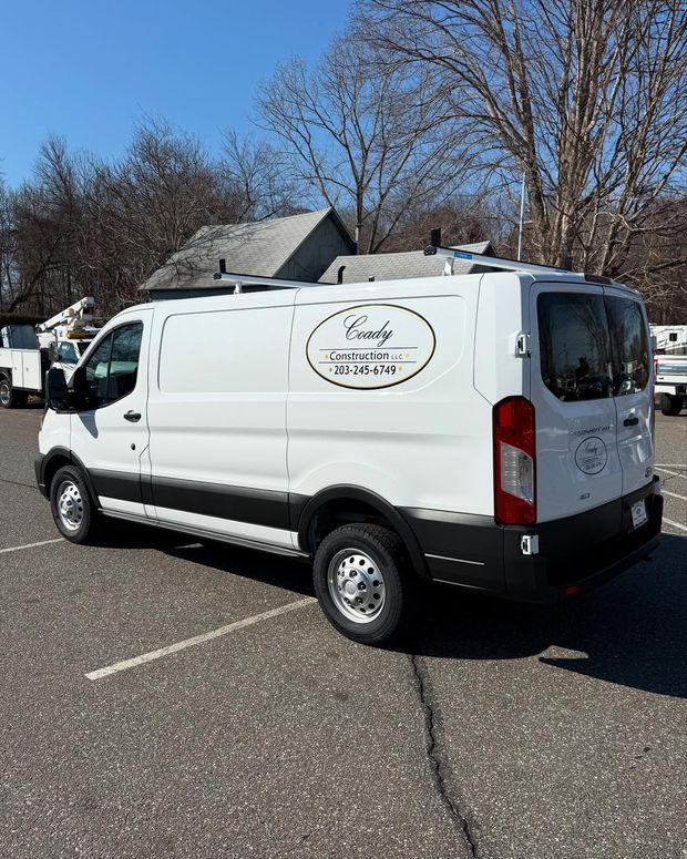 White work van with company logo parked in a lot on a sunny day.