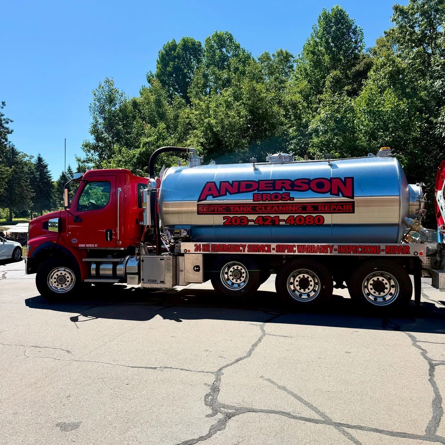 Red and silver Anderson Septic truck parked on cracked asphalt.