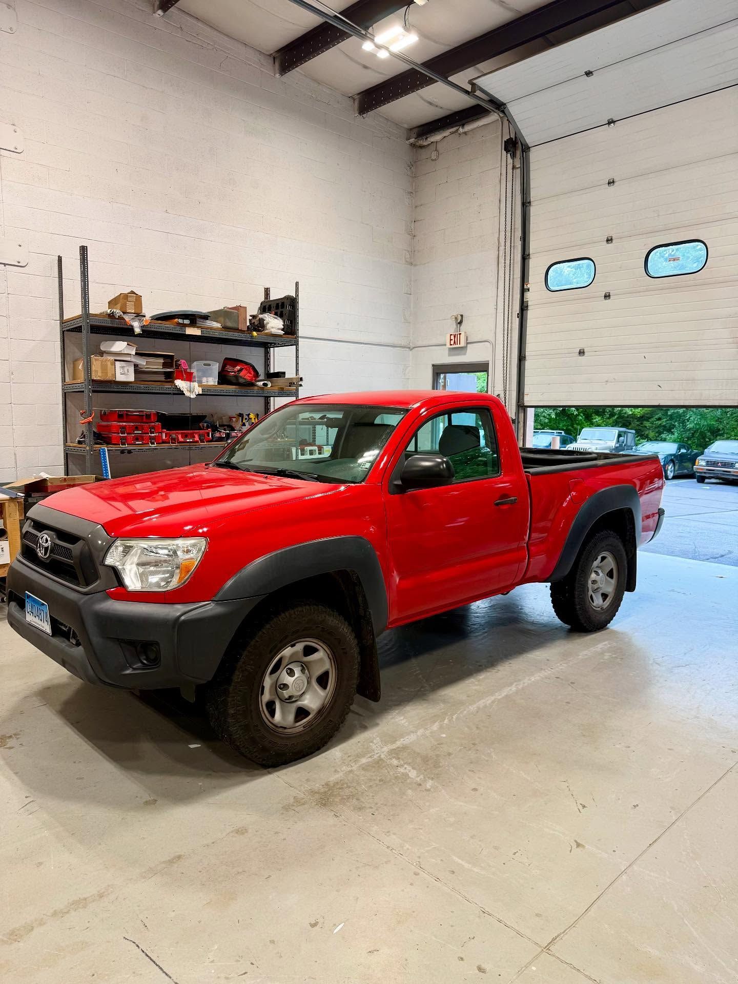 Red Toyota Tacoma truck parked inside a garage.