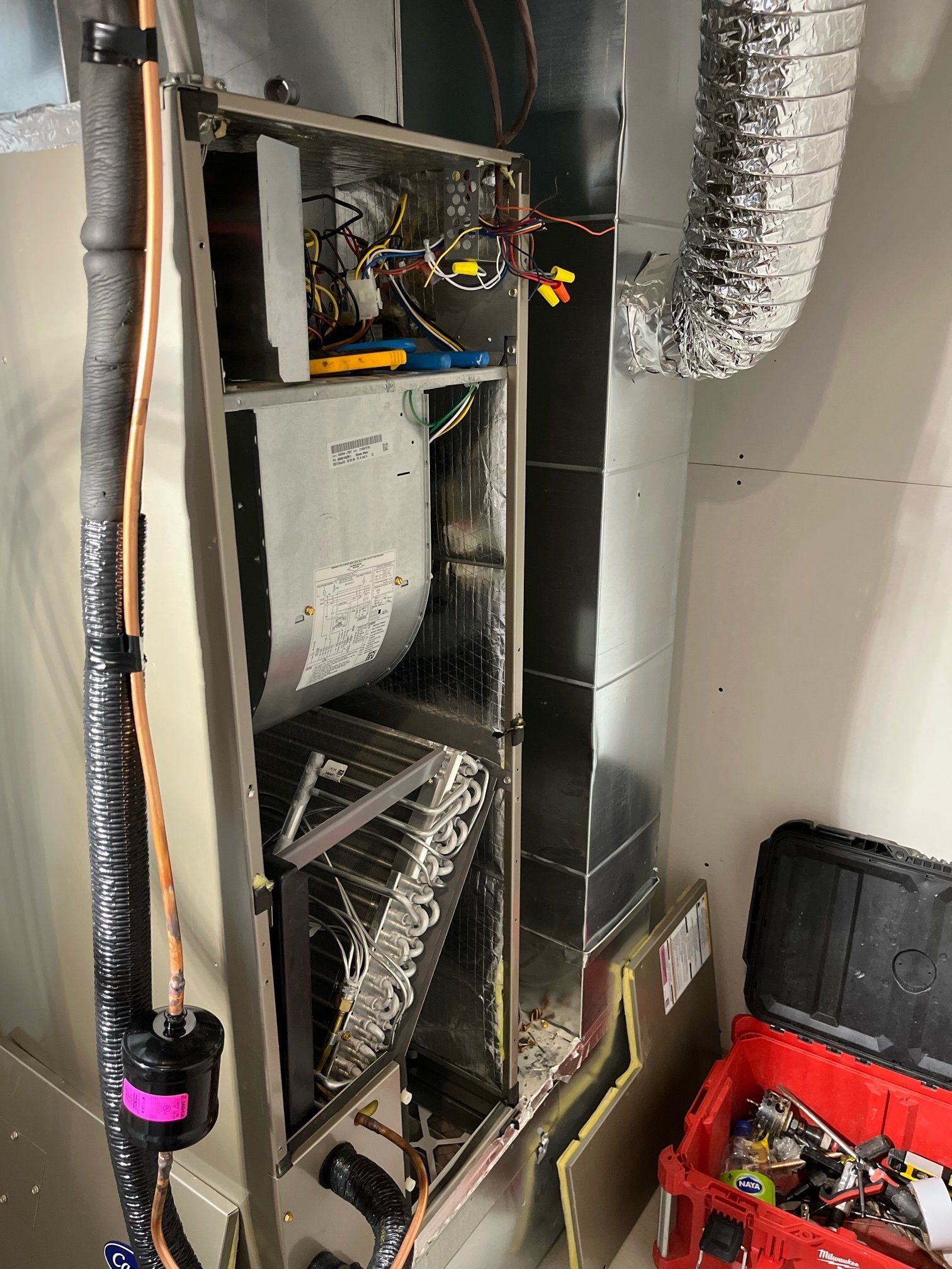 Un climatiseur est en cours de réparation dans une pièce avec une boîte à outils rouge.