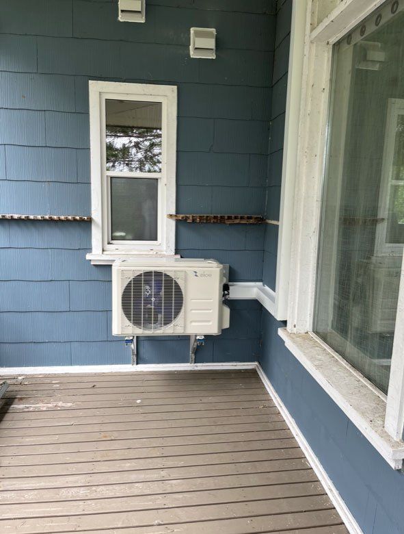 Une maison bleue avec un climatiseur blanc sur le côté.