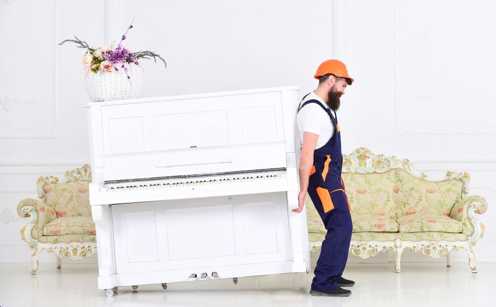 A Man Is Carrying a White Piano in A Living Room — Dawson Moving & Storage NQ in Cairns, QLD