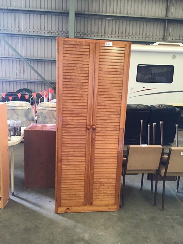 A Wooden Cabinet Is Sitting In A Warehouse Next To A RV — Dawson Moving & Storage NQ in Melbourne, VIC