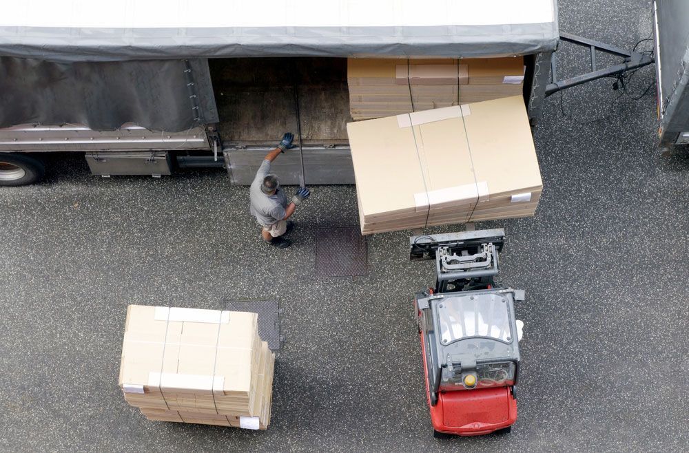 man behind the truck putting multiple big boxes inside the truck