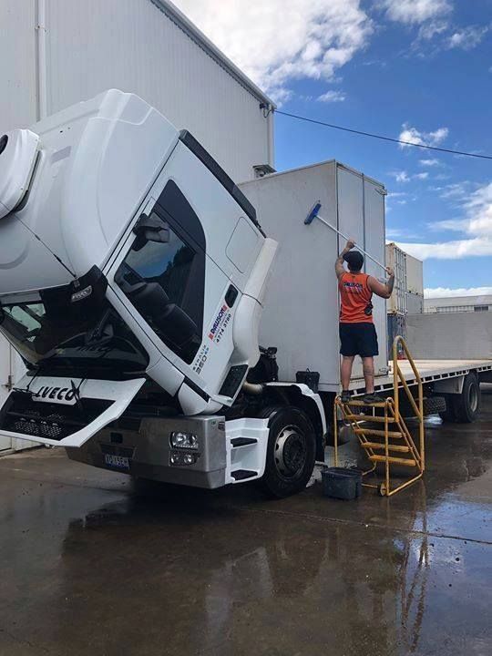 A Man Is Standing On A Ladder Next To A Truck With Its Hood Up — Dawson Moving & Storage NQ in Townsville, QLD