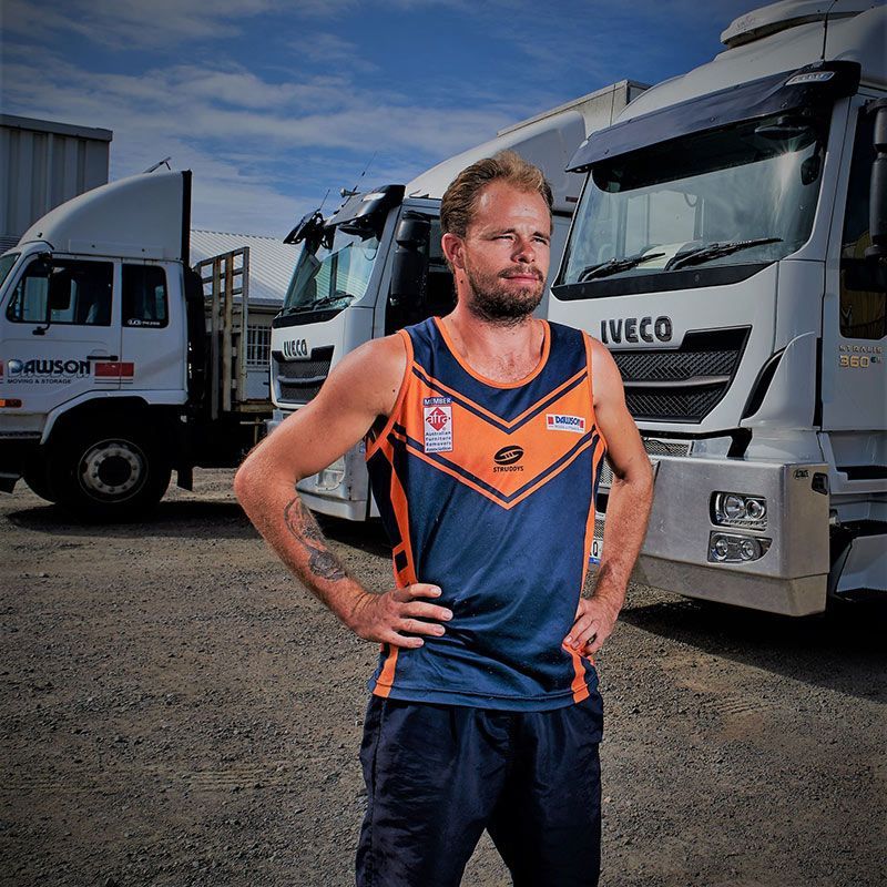 A Man Standing In Front Of A Row Of Iveco Trucks — Dawson Moving & Storage NQ in Townsville, QLD