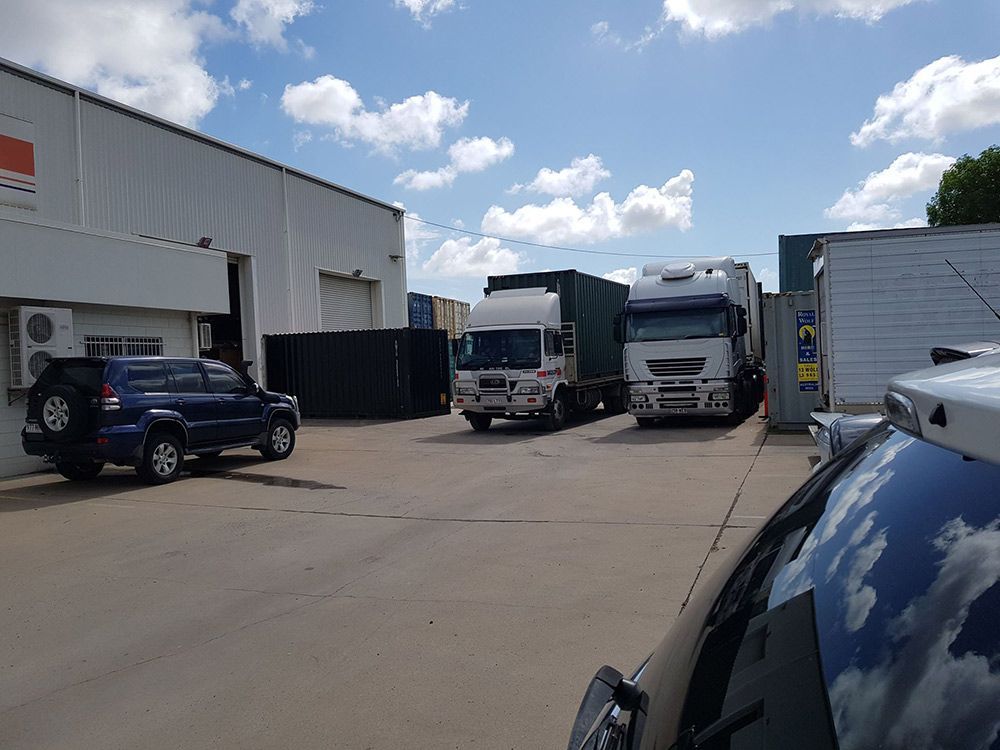 A Row Of Trucks Are Parked In Front Of A Building — Dawson Moving & Storage NQ in Mount St John, QLD