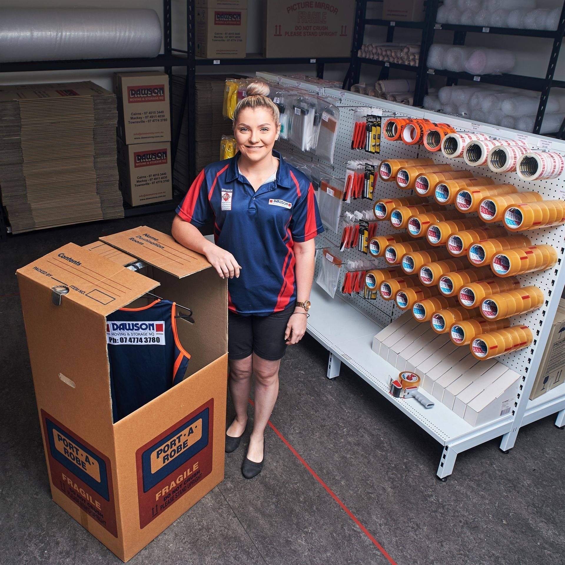 A Man In A Blue Shirt Is Carrying A Refrigerator Through A Doorway — Dawson Moving & Storage NQ in Mount St John, QLD