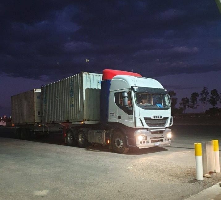 A Semi Truck With Container Storage Is Parked In A Parking Lot At Night — Dawson Moving & Storage NQ in Mount St John, QLD