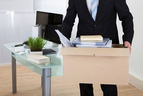 A Man In A Suit And Tie Is Carrying A Box Of His Belongings — Dawson Moving & Storage NQ in Mount St John, QLD
