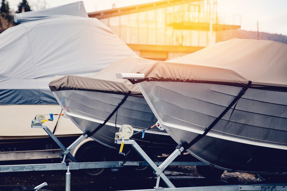 A Couple Of Boats Sitting On Top Of A Trailer Covered In A Tarp — Dawson Moving & Storage NQ in Mount St John, QLD
