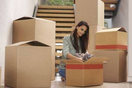 A Woman Is Kneeling On The Floor Surrounded By Cardboard Boxes — Dawson Moving & Storage NQ in Mount St John, QLD
