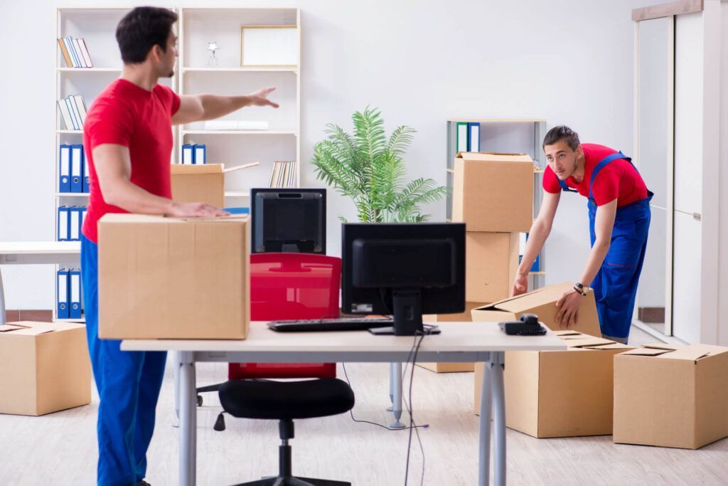 Two Men Are Moving Boxes in An Office — Dawson Moving & Storage NQ in Mount St John, QLD