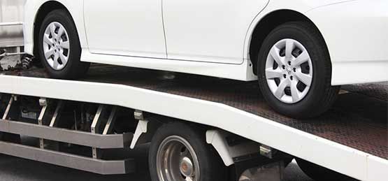 A White Car Is Sitting On Top Of A Tow Truck — Dawson Moving & Storage NQ in Mount St John, QLD