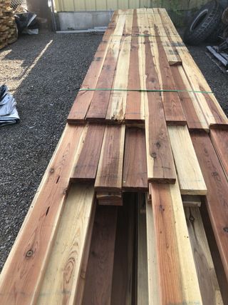 A stack of wooden boards sitting on top of each other on a gravel road.