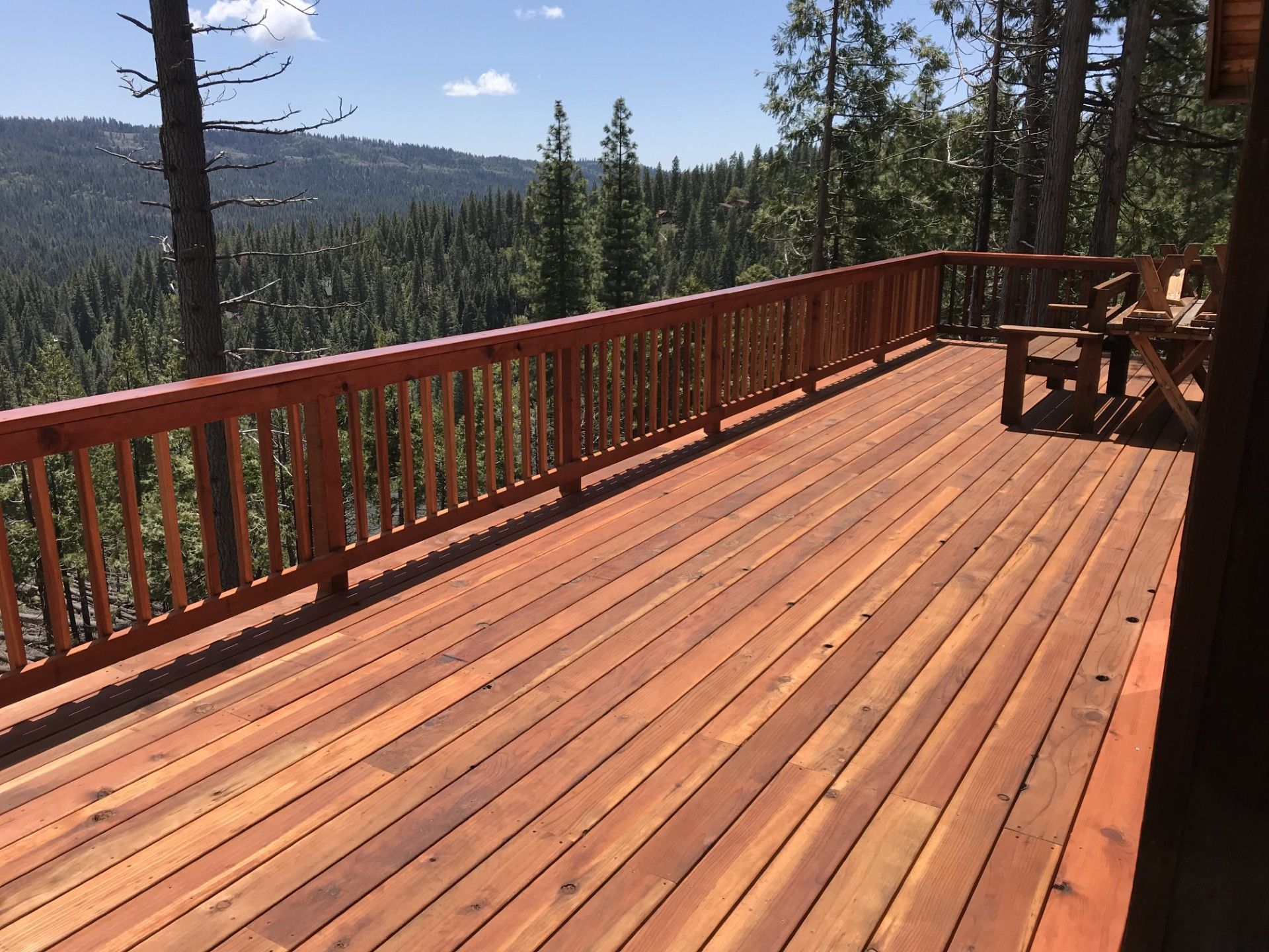 A large wooden deck with a view of a forest