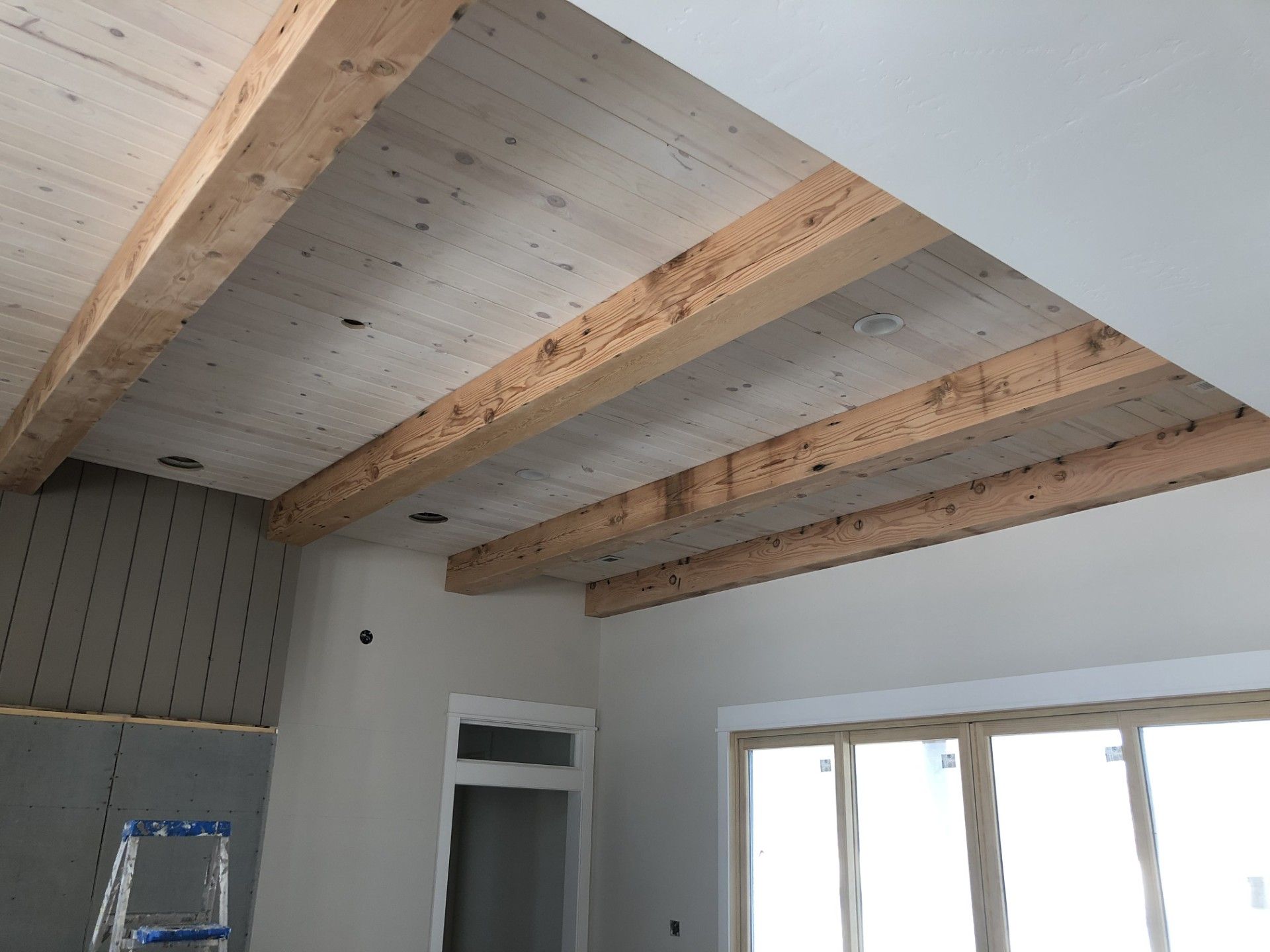 A room with a ladder and wooden beams on the ceiling